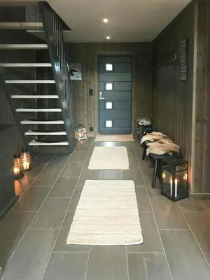 a hallway with rugs and a blue door and stairs at Large Cabin Near Hardangervidda With Sunny Veranda in Veggli