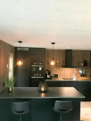 a kitchen with black cabinets and a counter with bar stools at Large Cabin Near Hardangervidda With Sunny Veranda in Veggli