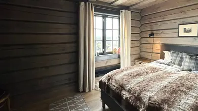 a bedroom with wooden walls and a bed and a window at Cozy Log Cabin With A View Over Hedmarken in Løten