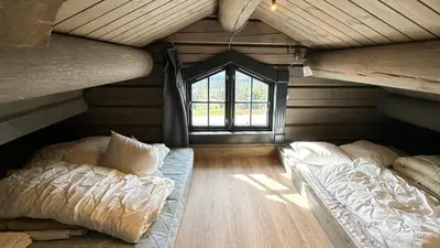 an attic room with two beds and a window at Cozy Log Cabin With A View Over Hedmarken in Løten