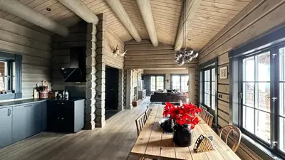 a dining room with a table with red flowers on it at Cozy Log Cabin With A View Over Hedmarken in Løten