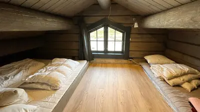 a bedroom with two beds in a room with a window at Cozy Log Cabin With A View Over Hedmarken in Løten