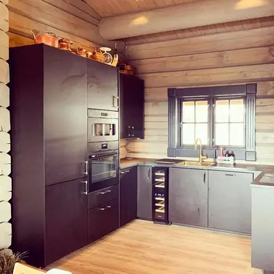 a kitchen with stainless steel appliances and wooden walls at Cozy Log Cabin With A View Over Hedmarken in Løten