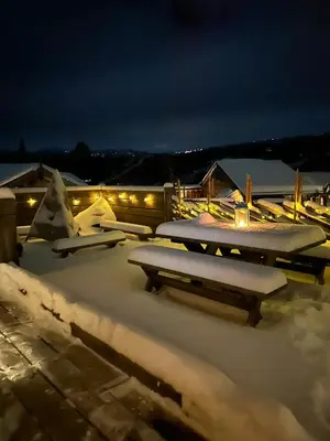 a snow covered patio with picnic tables and lights at Luxury Log Cabin By Hardangervidda in Uvdal