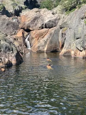 a person swimming in the water near some rocks at Luxury Log Cabin By Hardangervidda in Uvdal
