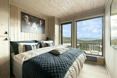 a bedroom with a large bed and a large window at Norefjell Cottage With Sauna And Whirlpool in Noresund