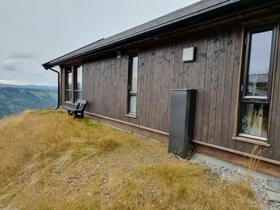 a building on top of a hill with a bench at Luxury Mountain Home With View On Gaustablikk in Rjukan