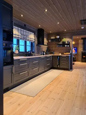 a kitchen with gray cabinets and a wooden floor at Modern Cabin With Ski Inout In Great Area in Brunstad
