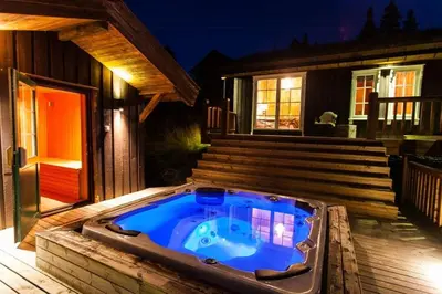 a hot tub on a deck in front of a house at Cozy Cabin In Uvdal With Jacuzzi And Sauna in Uvdal
