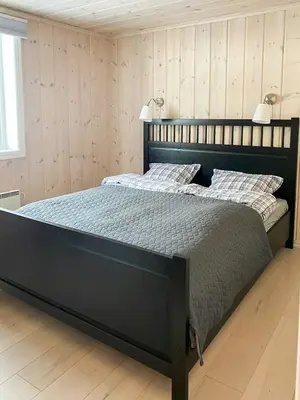 a bedroom with a large black bed with two lamps at Relax By The Ski Tracks In A Cabin At Sjusjøen in Sjusjøen