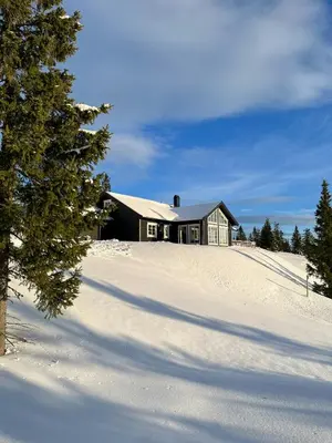 a house on top of a snow covered hill at Modern Mountain Cabin With Panoramic Views in Sjusjøen