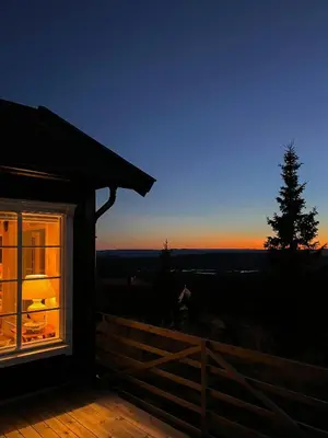 a view of the sunset from the porch of a house at Modern Mountain Cabin With Panoramic Views in Sjusjøen