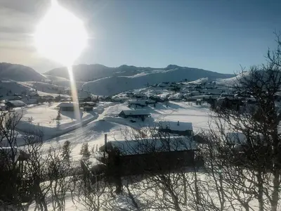 a village covered in snow with the sun in the sky at Charming Cabin Overlooking Vegglifjell in Kravikfjord