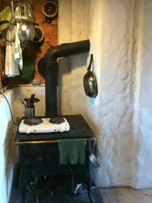 an old stove in a kitchen with a pot at Charming Artist's Cabin With Sea View Near Bergen in Straume
