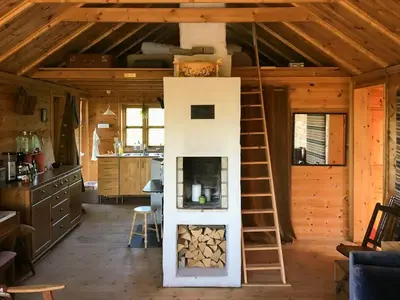 a fireplace in a log cabin with a ladder at Charming Artist's Cabin With Sea View Near Bergen in Straume