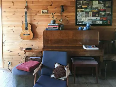 a room with a piano and a chair and a guitar at Charming Artist's Cabin With Sea View Near Bergen in Straume