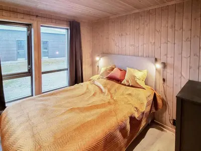a bedroom with a bed and two windows at Stylish Modern Cabin In Charming Kvitfjell in Favang