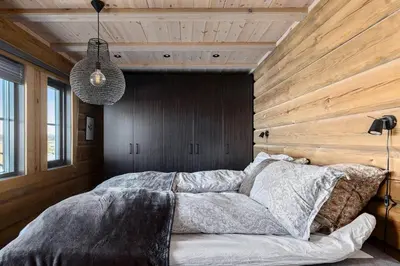 a bedroom with a large bed with a wooden wall at Modern And Spacious Cabin At Mosetertoppen in Øyer