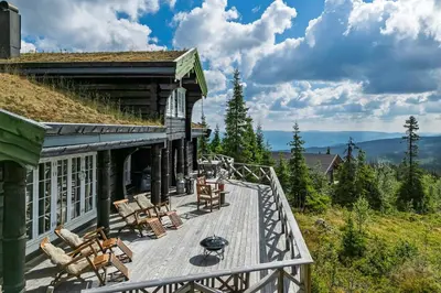 a deck with chairs and tables on a house at Cozy And Spacious Family Cabin In Valdres in Bagn