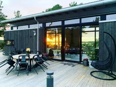 a patio with a table and chairs on a deck at Peaceful Nature And Design On Skardsøya in Lesund