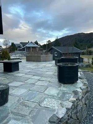 a patio with two trash cans and a stone wall at Charming Cabin With Archipelago Views In Sogn in Ånneland