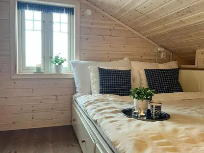 a bed in a room with wooden walls and windows at Family Cabin With Panoramic View Near Vikerfjellet in Hønefoss