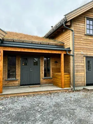 a wooden house with a black door and a porch at Modern Family Cabin At Vegglifjell in Veggli