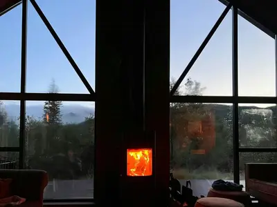 a fire burns in a fireplace in a room with windows at Modern Family Cabin At Vegglifjell in Veggli