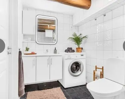 a white bathroom with a washing machine and a sink at Stilig bryggeleilighet i Trondheim sentrum in Trondheim