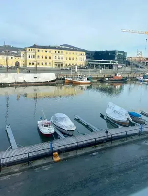 two boats are docked at a dock in a harbor at Stilig bryggeleilighet i Trondheim sentrum in Trondheim