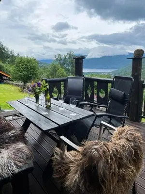 a wooden table and chairs on a wooden deck with a dog at Fantastic Charming Cabin By Tinnsjøen in Austbygdi