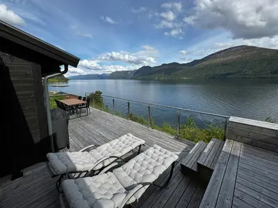 a deck with couches and a view of a lake at Luxury By The Fjord In Ranvik in Eidsvåg