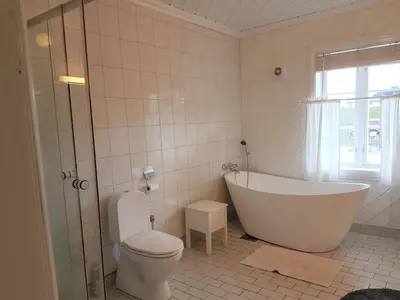 a white bathroom with a tub and a toilet at Charming sea house with sauna and private jetty in Ølve