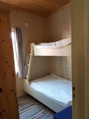 two bunk beds in a room with a window at Charming sea house with sauna and private jetty in Ølve