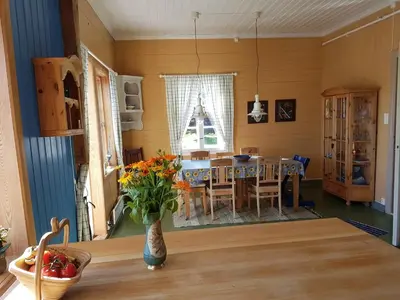 a dining room with a table and a vase of flowers at Charming sea house with sauna and private jetty in Ølve