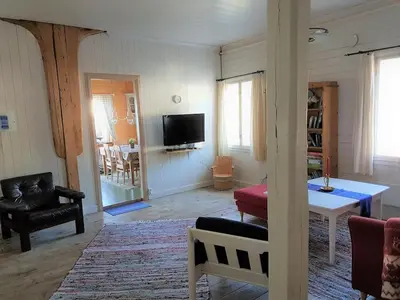 a living room with a table and a tv at Charming sea house with sauna and private jetty in Ølve