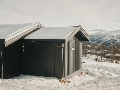 a black building with snow on the roof in the snow at Cabin In Uvdal With A View Ski-Inout in Uvdal
