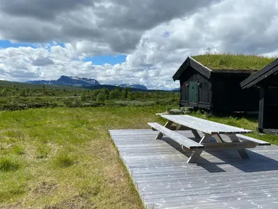 a wooden picnic table sitting on a field with a hut at Spacious Family Cabin Near Nordre Syndin in Ryfoss