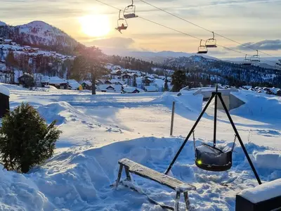 a bench in the snow next to a ski lift at 9 person holiday home in Rauland in Rauland
