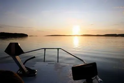 a boat in the water with the sun setting at Old Fishermans Home By Mjosundet In Aure in Valen
