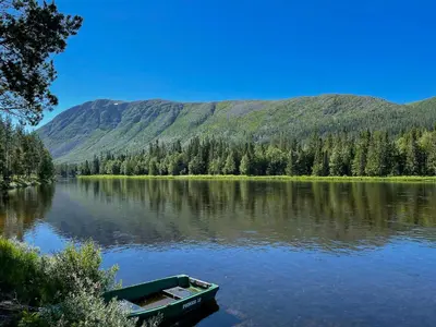a boat on a lake with mountains in the background at Cabin With Great Fishing At Trysilfjellet in Jordet