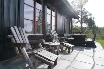 a patio with chairs and a table and a grill at Moderne hytte plass for 10 in Rendalen