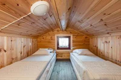 two beds in a room with wooden walls at Moderne hytte plass for 10 in Rendalen