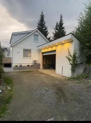 a white house with a garage and a driveway at et fint og stort enebolig sentralt i voss! in Vossevangen