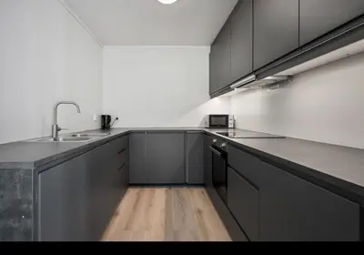 a kitchen with black cabinets and a wooden floor at et fint og stort enebolig sentralt i voss! in Vossevangen