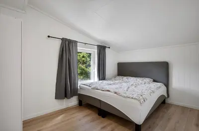a white bedroom with a bed and a window at et fint og stort enebolig sentralt i voss! in Vossevangen