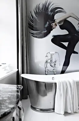 a bathroom with a bath tub and a picture of a woman at Hotel Oleana in Bergen