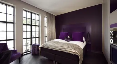 a bedroom with purple walls and a bed with purple pillows at Hotel Oleana in Bergen