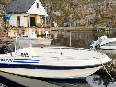 a white boat is docked in the water near a house at 4 person holiday home in Kjerrgarden in Kjerrgarden