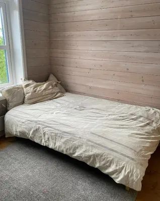a bed in a room with a wooden wall at SKI VM House 5 min walk to Granåsen ski stadion in Trondheim